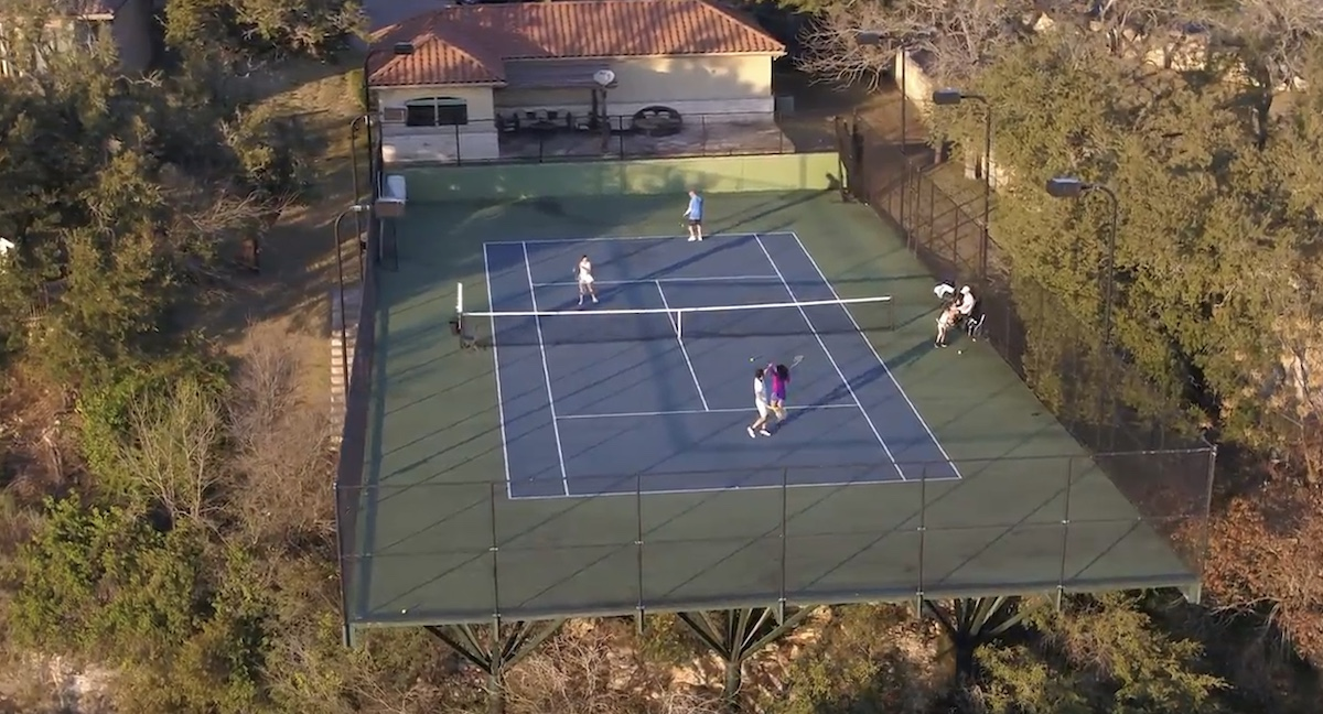 Aerial view of an elevated tennis court above the tree line